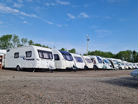 row of caravans parked in a gravel lot under a clear blue sky showcasing various models and designs ideal for 3 trips or more