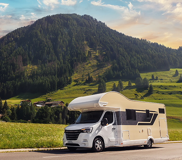 a modern RV parked on a scenic road with mountains in the background surrounded by greenery perfect for a 6 day adventure or vacation