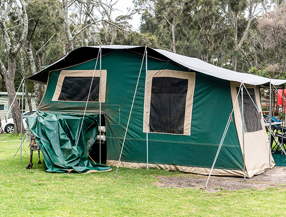 a large green camping tent with multiple entrances and windows set up on grass surrounded by trees ideal for outdoor adventures including family trips or gatherings with a capacity of seven people